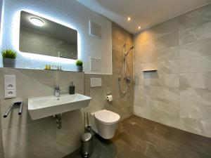 a bathroom with a sink and a toilet and a shower at Auszeit Apartment STYLE in Friedrichshafen