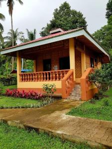 ein kleines Haus mit Gelb und Orange in der Unterkunft Paco's Garden Home Stay in Mambajao