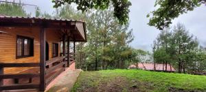 Cabaña La Vía Láctea في El Pacífico: كابينة خشب بها ساحة خضراء بجوار منزل