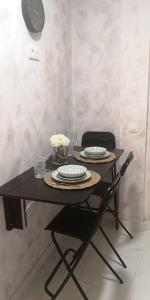 uma mesa preta com duas cadeiras e pratos em Tranquila casa con patio em Vigo