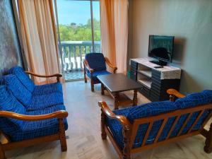 d'un salon avec des chaises, une télévision et un balcon. dans l'établissement Glory beach seaview resort 2 bedroom, à Port Dickson