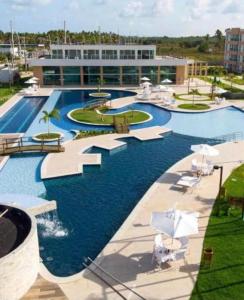 ein großes Schwimmbad mit Stühlen und einem Gebäude in der Unterkunft Flat Garden 113 Muro Alto Condominio Clube in Porto De Galinhas