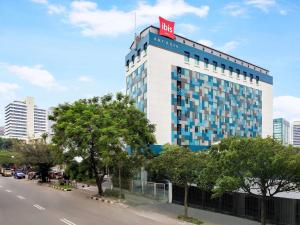 a building with a red sign on top of it at Ibis Jakarta Arcadia in Jakarta