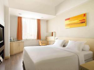 a hotel room with a white bed and a television at Ibis Jakarta Arcadia in Jakarta