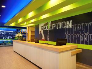 a reception desk in a store with a reputation sign on the wall at Ibis Budget Jakarta Daan Mogot in Jakarta