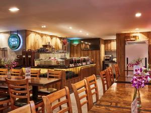 a restaurant with wooden tables and chairs and a kitchen at ibis budget Singapore Selegie in Singapore