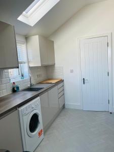 a white kitchen with a washing machine in it at Castle view Rochester in Rochester +22 photos