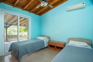 Habitación azul con 2 camas y ventana en Villa Hercules, en Kremasti