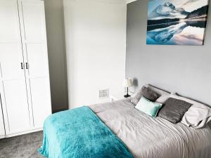a bedroom with a bed with a blue blanket and pillows at Newly Refurbished 2 Bedroom Flat - Long stays AVL in Norbury