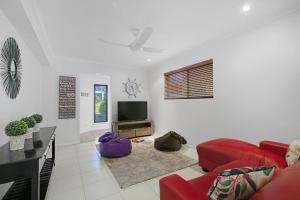 a living room with a red couch and a flat screen tv at Ivy Street 7 Dicky Beach in Caloundra
