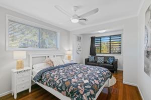 a bedroom with a bed and a chair and windows at Ivy Street 7 Dicky Beach in Caloundra