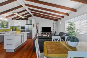 a kitchen and living room with white walls and wooden ceilings at Ivy Street 7 Dicky Beach in Caloundra