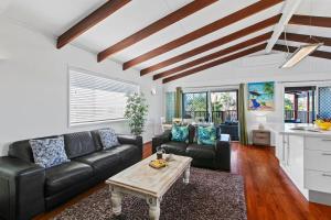 a living room with a black leather couch and a table at Ivy Street 7 Dicky Beach in Caloundra