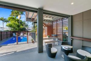 an outdoor patio with tables and chairs and a swimming pool at Ivy Street 7 Dicky Beach in Caloundra