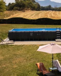 a pool with an umbrella and a chair and a table with an umbrella at Vikendice Stara Pruga in Gornji Milanovac