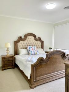 1 dormitorio con 1 cama grande con marco de madera en Dylan的小屋, en Point Cook