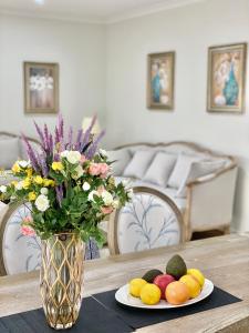 un jarrón con flores y fruta en una mesa en Dylan的小屋, en Point Cook