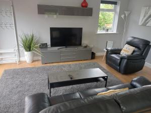 uma sala de estar com um sofá de couro preto e uma televisão de ecrã plano em Green Street Retreat em York