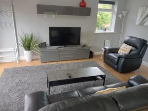 a living room with a black leather couch and a flat screen tv at Green Street Retreat in York