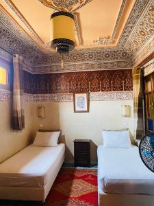 two beds sitting in a room with a ceiling at Riad Dar Essassi 23 in Marrakech