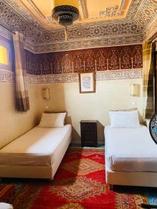 two beds in a room with a ceiling at Riad Dar Essassi 23 in Marrakesh