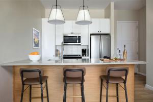 a kitchen with a counter with three bar stools at Sentral Old Town in Scottsdale