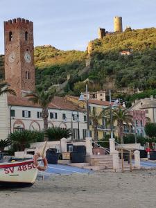 una barca sulla spiaggia con torre dell'orologio di Residenza Tra Le Torri a Noli