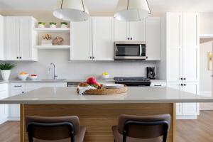 a kitchen with white cabinets and a table with a basket of fruit at Sentral Old Town in Scottsdale