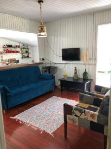 ein Wohnzimmer mit einem blauen Sofa und einem Fernseher in der Unterkunft Hospedaria Rural Recanto Verde dos Canyons in Praia Grande