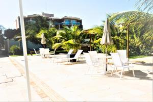 a patio with white chairs and tables and umbrellas at BEACH PARK PALM - COBERTURA Luxo in Aquiraz