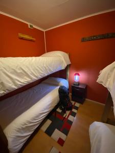 a room with two bunk beds and a table with a lamp at Konkashken Lodge in Torres del Paine