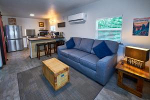 a living room with a blue couch and a kitchen at Steps from Downtown Pigeon Forge Parkway + Private Hottub and firepit - Wifi - Firefly Bungalows in Pigeon Forge