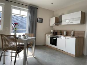 eine Küche mit weißen Schränken, einem Tisch, einem Tisch und Stühlen in der Unterkunft Studio - Apartment Steinmetz mit Balkon in Reken