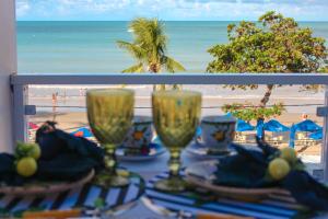 a table with glasses and a view of the beach at Pousada Recanto da Família in Natal