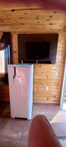ein kleiner weißer Kühlschrank in einem Zimmer mit einem TV in der Unterkunft Cabana Campinho II in Mundo Novo