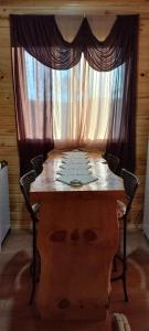 einen Tisch mit 2 Stühlen und ein Fenster mit Vorhängen in der Unterkunft Cabana Campinho II in Mundo Novo