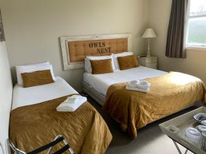 2 łóżka w pokoju hotelowym z ręcznikami w obiekcie FatOwl Motel, Bar & Eatery w mieście Piopio