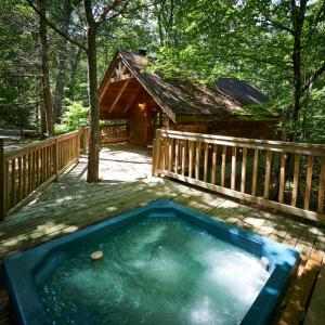 a hot tub on a deck next to a cabin at Gatlinburg Area Hottub Cabin - Ladyslipper in Sevierville