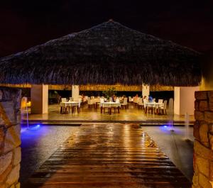 un restaurante con mesas y sillas y techo de paja en Entremonte Wellness Hotel and Spa, en Apulo