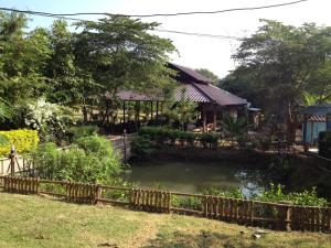 a pond in front of a house with a fence at Paipunthong Resort in Pai