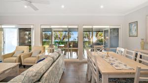 a living room with a long table and chairs at Sunset Beach Luxury 24 in Soldiers Point