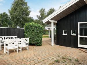 un patio con sillas blancas y un edificio negro en Holiday home Otterup XVIII, en Otterup
