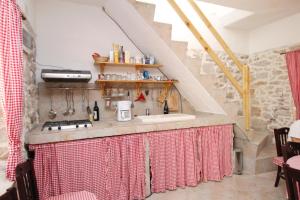 a kitchen with a sink and a counter with red curtains at Holiday house with a parking space Lukoran (Ugljan) - 6234 in Lukoran +9 photos