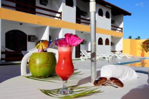 a drink on a table with a flower in a glass at Andimar Hotel in Porto Seguro