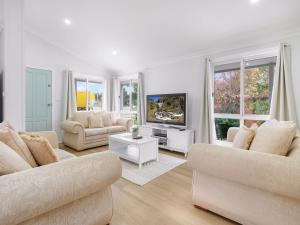 a white living room with two couches and a tv at 61 Myack Street in Berridale