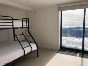 een slaapkamer met een stapelbed en een groot raam bij Arlberg 204 Ski-In Ski-Out Studio Apartment in Mount Buller