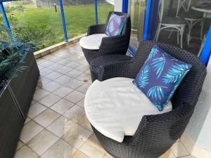 two wicker chairs with blue and purple pillows on a patio at Heritage unit 101 in Tuncurry