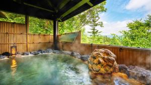 Hachimantai Mountain Hotel & Spa في Hachimantai: حوض استحمام ساخن مع صخرة في الفناء الخلفي