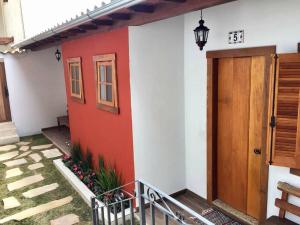 une maison rouge et blanche avec une porte dans l'établissement Chalés do Alferes, à Tiradentes