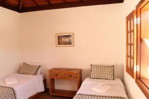 Cette chambre comprend 2 lits et une table en bois. dans l'établissement Chalés do Alferes, à Tiradentes